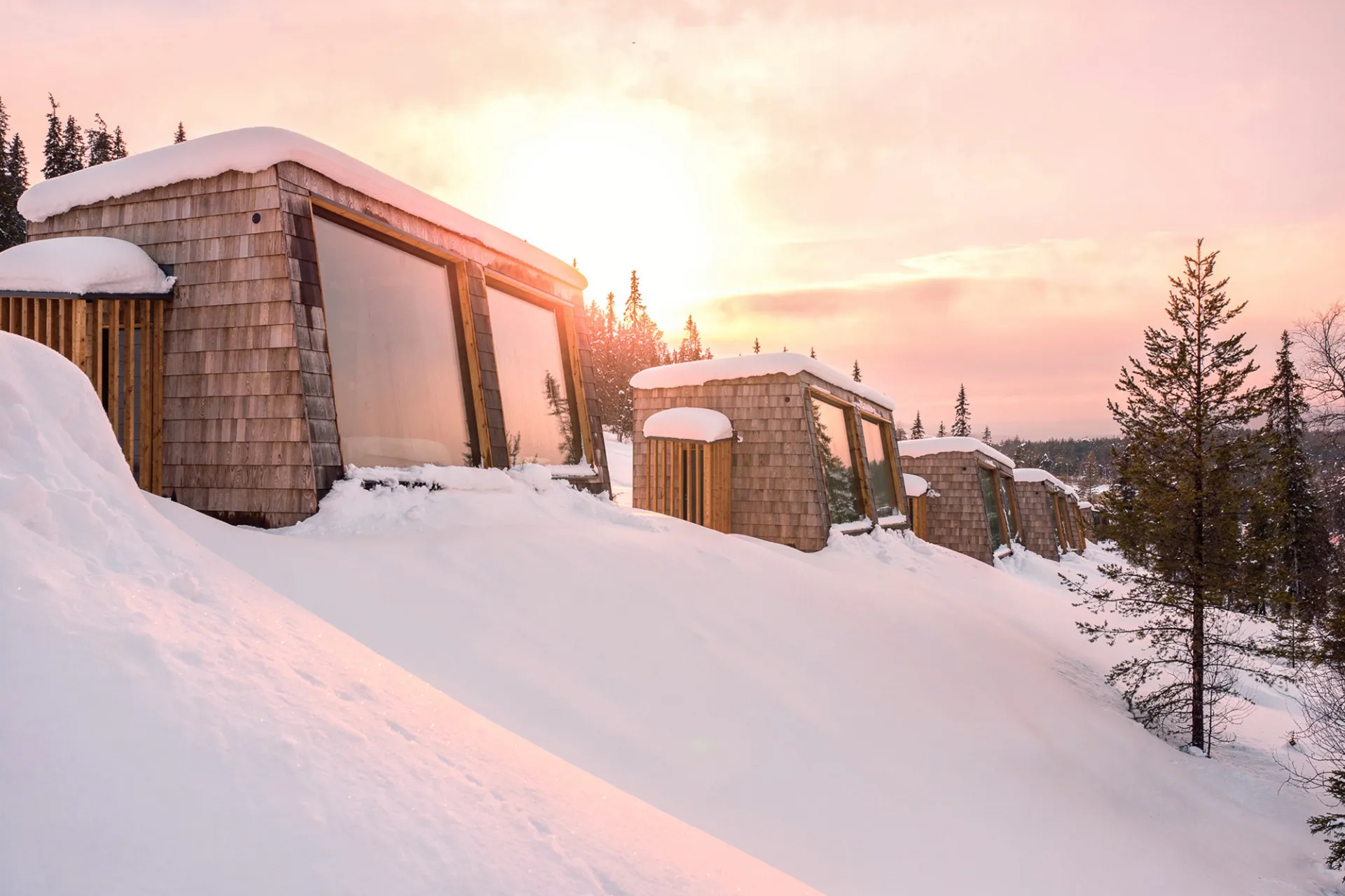 Paysage hivernal, chalets sous la neige au coucher du soleil