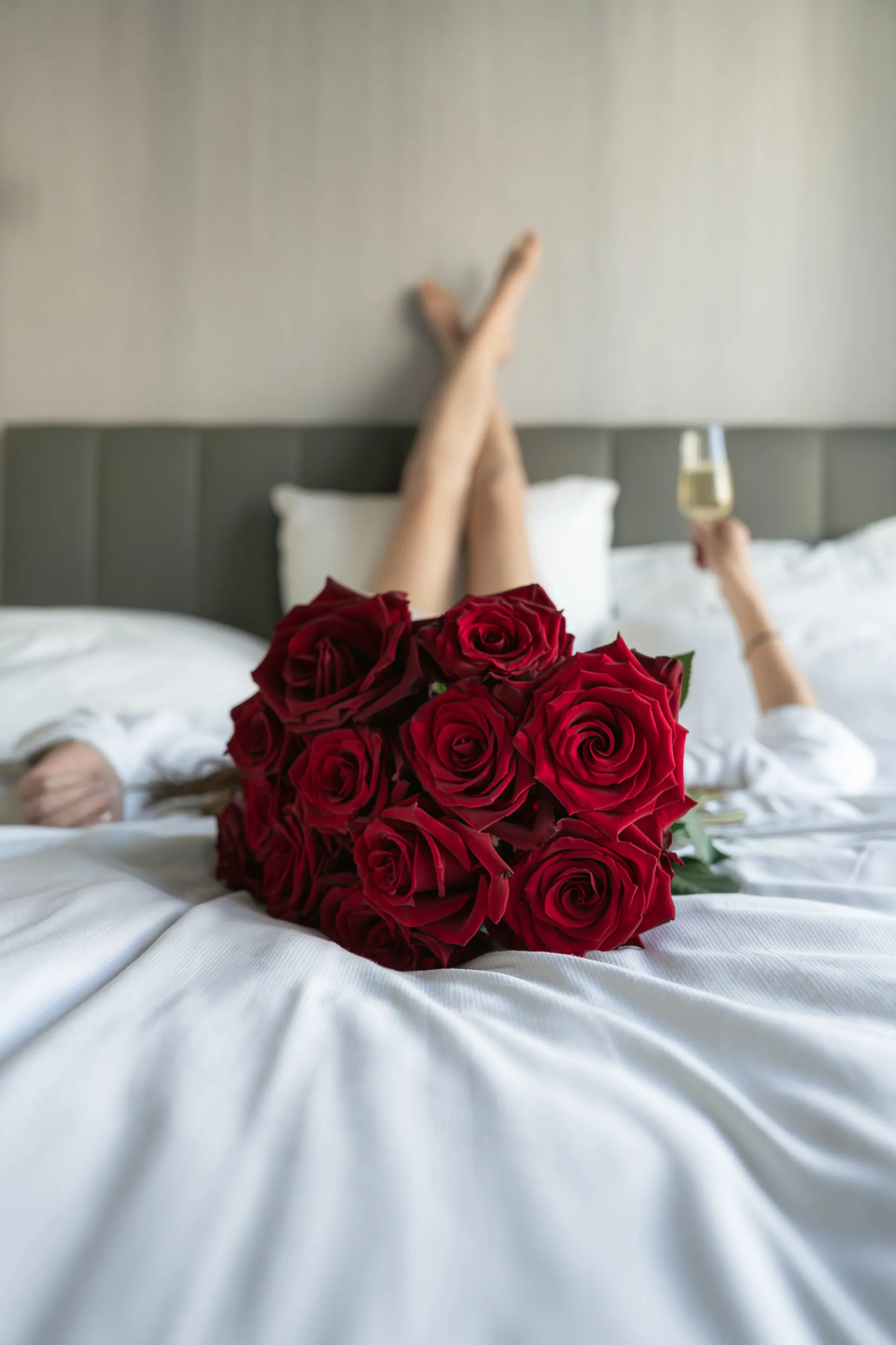 Bouquet de roses rouges et coupe de champagne sur un lit
