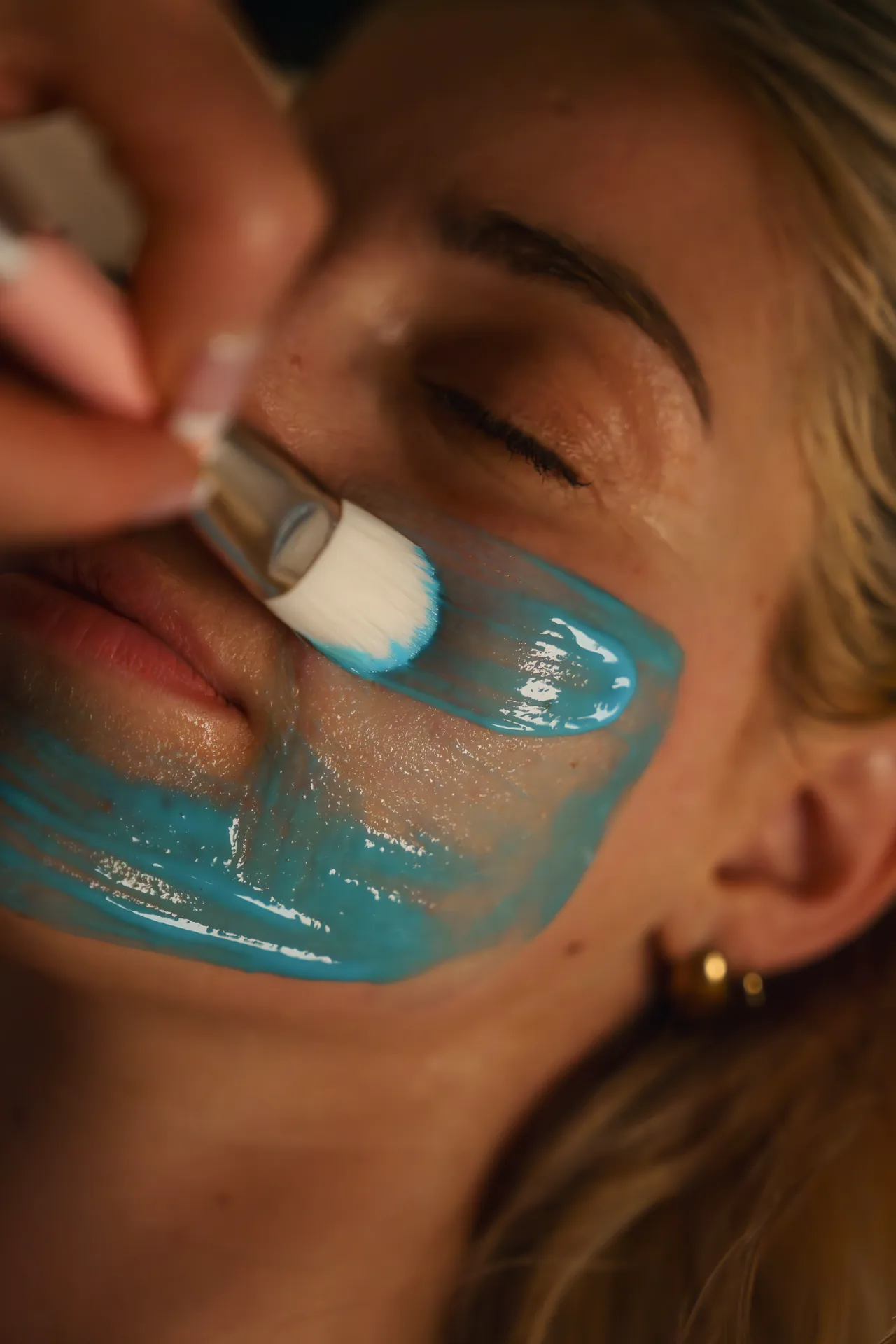 Soin du visage avec masque bleu au spa, pinceau esthétique